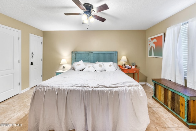 bedroom with ceiling fan, light tile patterned flooring, and a textured ceiling