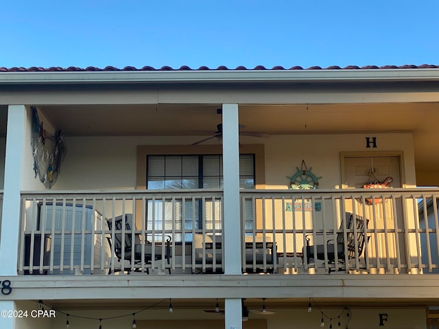 back of house with ceiling fan and a balcony