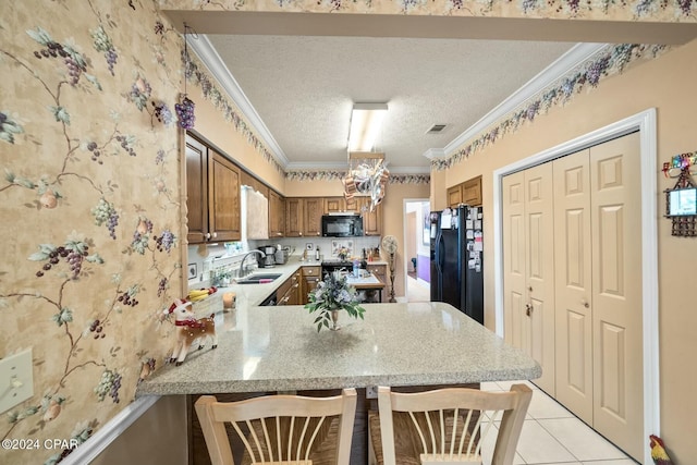 kitchen featuring black appliances, light tile patterned floors, a textured ceiling, kitchen peninsula, and a breakfast bar area