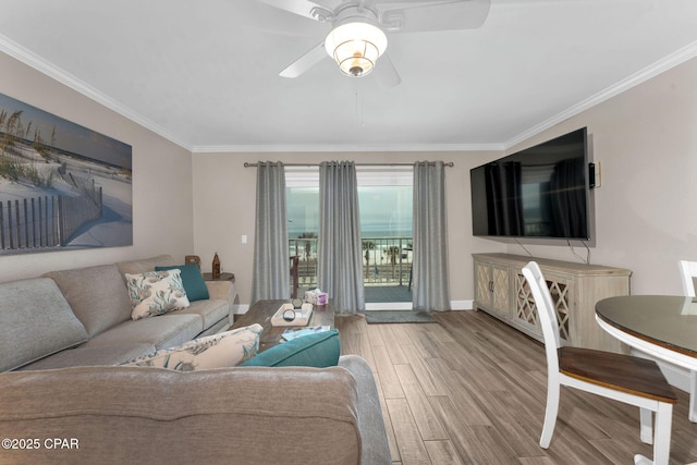 living area featuring a ceiling fan, crown molding, wood finished floors, and baseboards