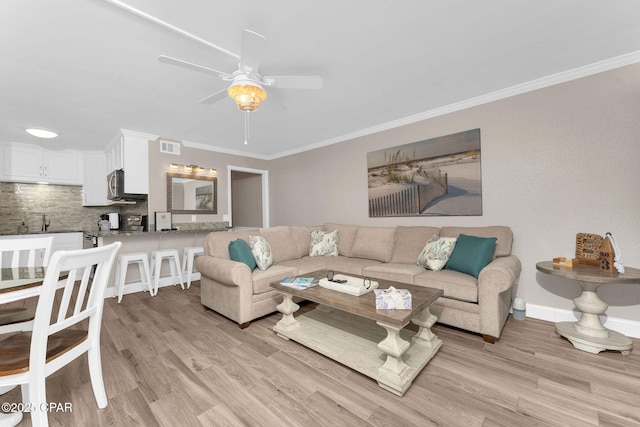 living room with ceiling fan, light wood-type flooring, visible vents, and ornamental molding