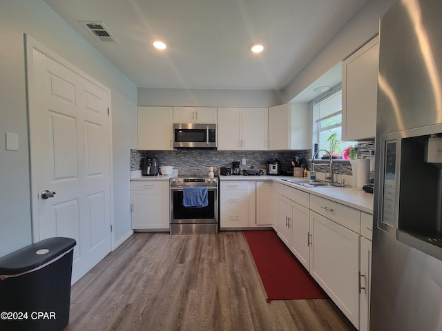 kitchen with sink, hardwood / wood-style flooring, tasteful backsplash, white cabinetry, and stainless steel appliances