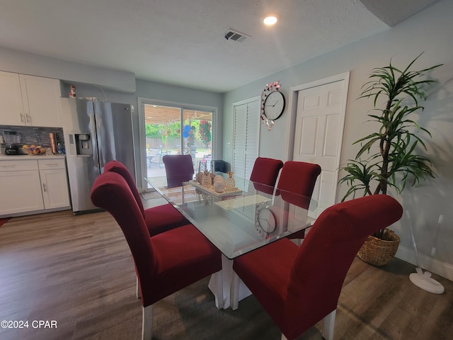 dining space with a textured ceiling and light hardwood / wood-style flooring