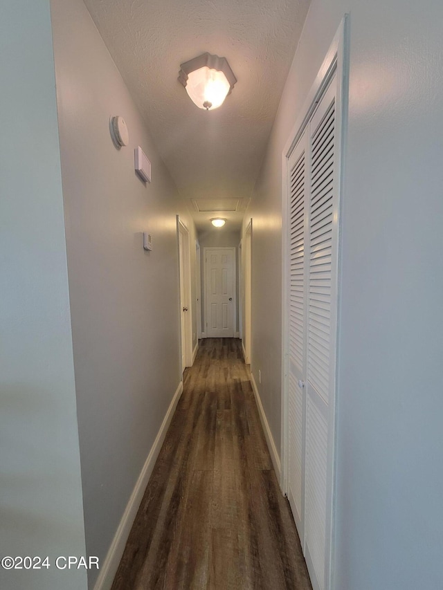 hall with a textured ceiling and dark hardwood / wood-style floors