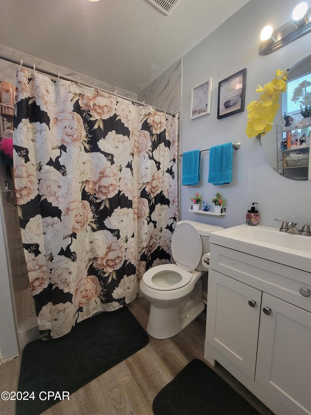 bathroom with a shower with shower curtain, vanity, a textured ceiling, hardwood / wood-style floors, and toilet