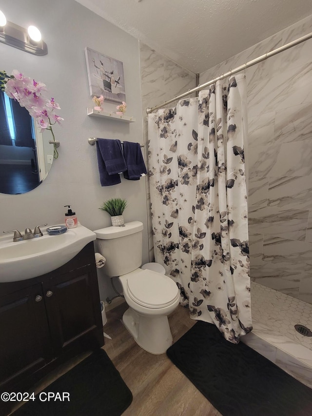 bathroom with hardwood / wood-style flooring, vanity, toilet, and walk in shower