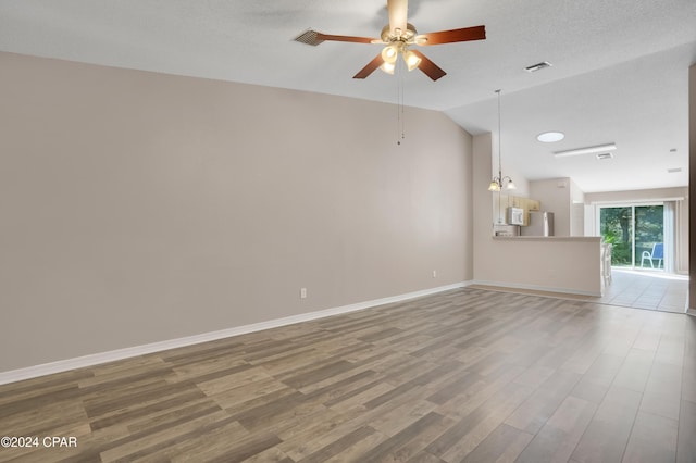 unfurnished living room with a textured ceiling, hardwood / wood-style flooring, vaulted ceiling, and ceiling fan