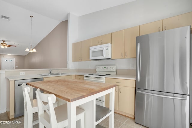 kitchen featuring sink, hanging light fixtures, kitchen peninsula, vaulted ceiling, and appliances with stainless steel finishes