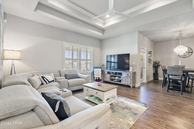 living room featuring a tray ceiling, dark hardwood / wood-style flooring, ceiling fan with notable chandelier, and ornamental molding