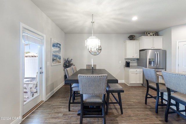 dining area with dark wood-type flooring and an inviting chandelier