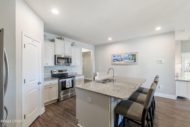 kitchen featuring light stone countertops, a kitchen breakfast bar, stainless steel appliances, sink, and a center island with sink