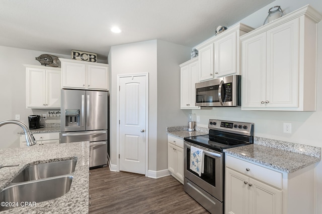 kitchen with light stone counters, stainless steel appliances, dark wood-type flooring, sink, and white cabinets