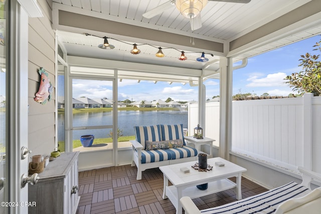 sunroom featuring ceiling fan and a water view