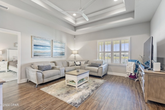 living room featuring a raised ceiling, ceiling fan, dark hardwood / wood-style flooring, and crown molding