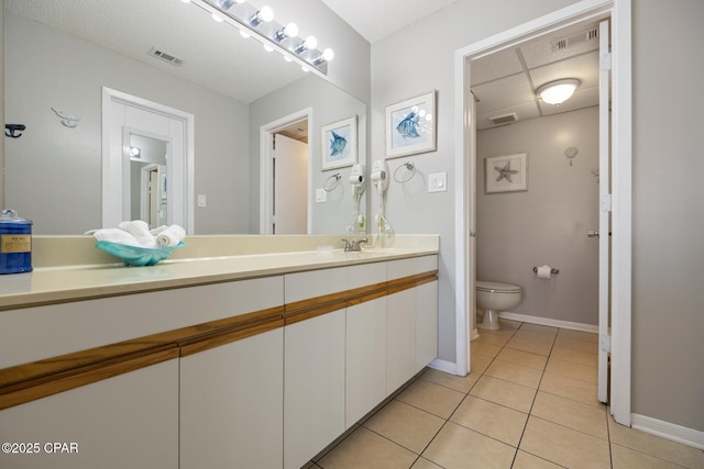 bathroom featuring tile patterned flooring, vanity, a paneled ceiling, and toilet