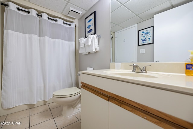 bathroom featuring tile patterned flooring, vanity, toilet, and a drop ceiling