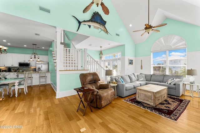 living room with ceiling fan, light hardwood / wood-style floors, and high vaulted ceiling