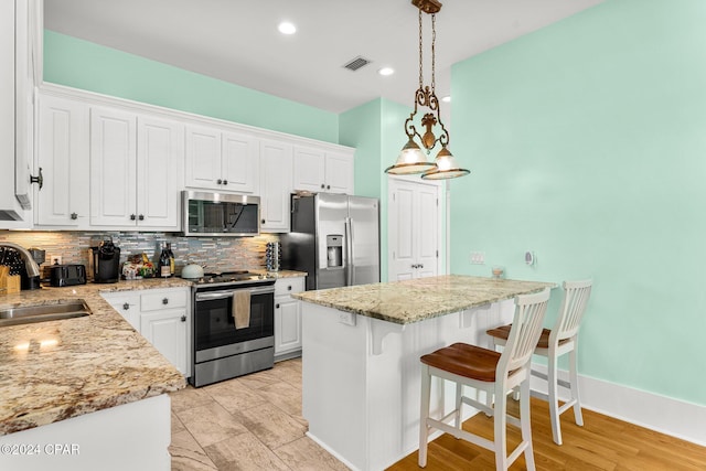 kitchen featuring sink, hanging light fixtures, light wood-type flooring, white cabinetry, and stainless steel appliances