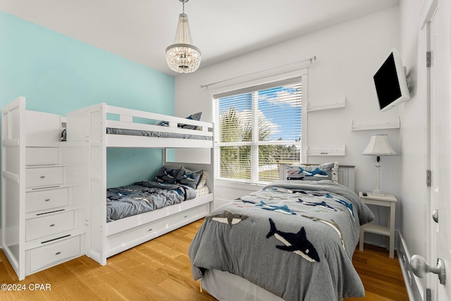 bedroom with light hardwood / wood-style floors and a notable chandelier