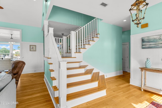 stairs featuring hardwood / wood-style flooring, a notable chandelier, and a high ceiling