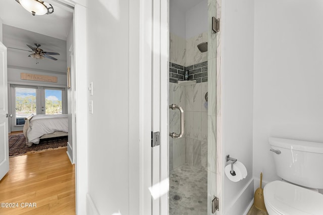 bathroom with wood-type flooring, toilet, ceiling fan, and a shower with shower door