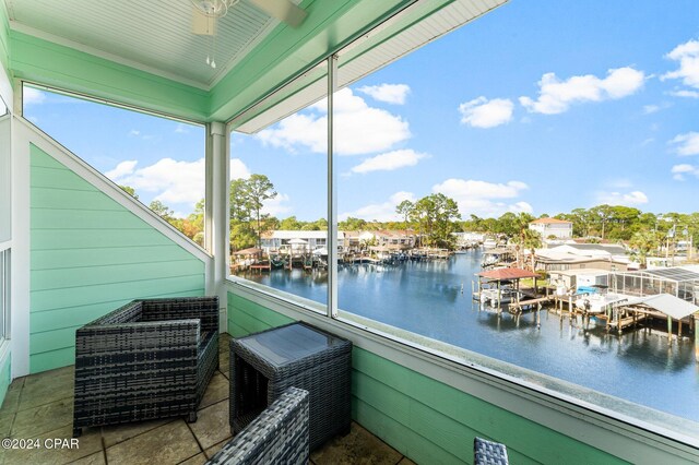 exterior space with ceiling fan, a water view, and a boat dock