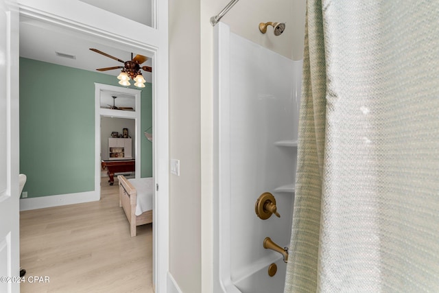 bathroom featuring ceiling fan, shower / bathtub combination with curtain, and wood-type flooring