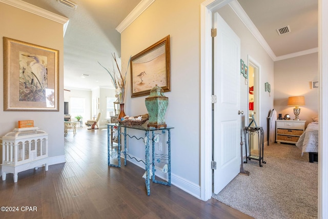 hallway featuring ornamental molding, visible vents, baseboards, and wood finished floors