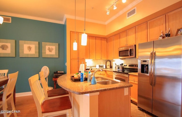 kitchen with pendant lighting, a center island with sink, sink, ornamental molding, and appliances with stainless steel finishes