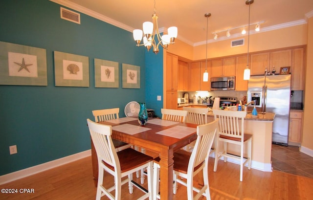 dining area featuring wood-type flooring, a notable chandelier, and ornamental molding