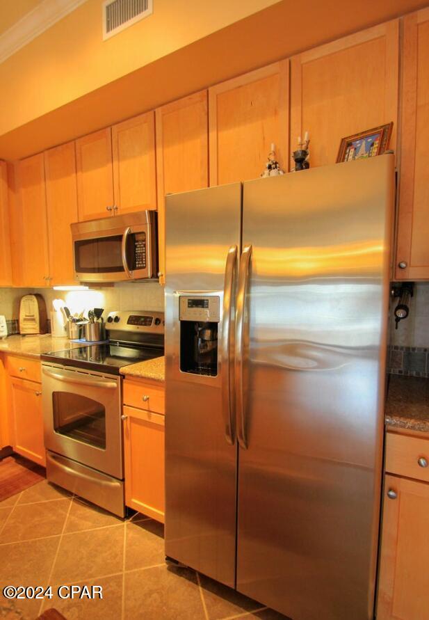 kitchen with decorative backsplash, appliances with stainless steel finishes, light tile patterned floors, and crown molding