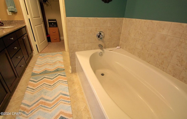 bathroom with tile patterned floors, tiled tub, and vanity