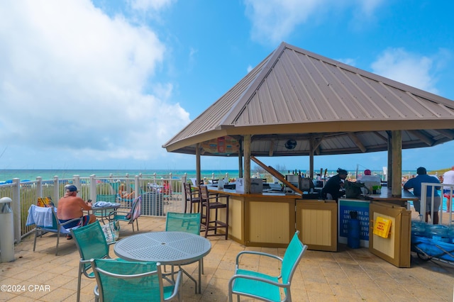 view of patio / terrace with a beach view, a water view, and a gazebo