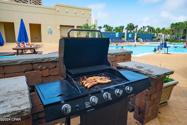 view of patio / terrace featuring a fire pit, a community pool, and grilling area