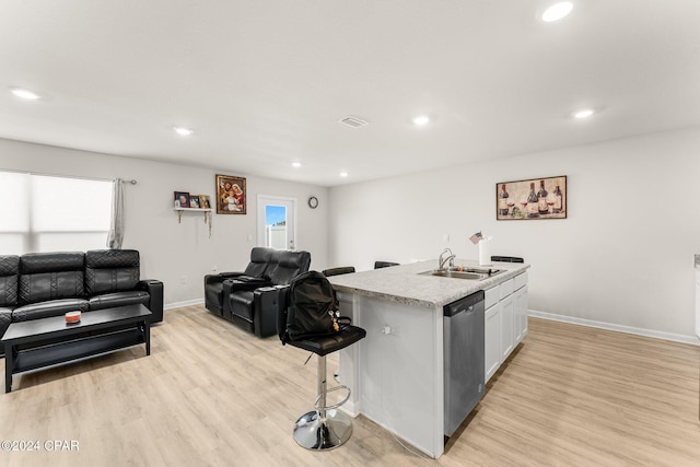 kitchen with sink, stainless steel dishwasher, a breakfast bar, white cabinets, and a center island with sink