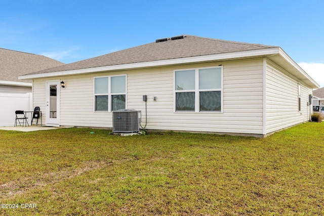 back of property with central AC unit, a patio area, and a yard