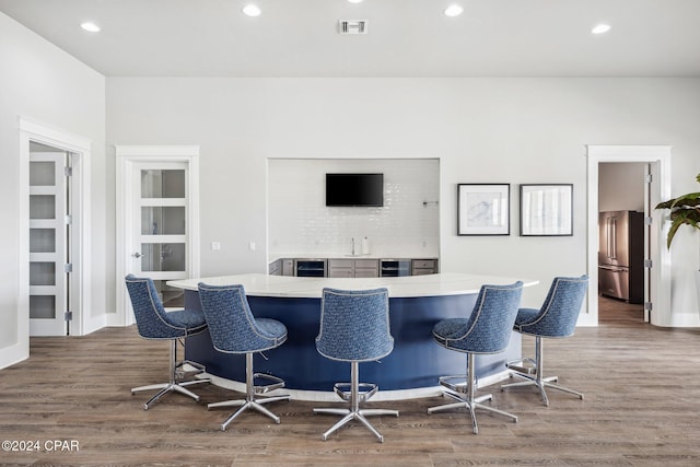 bar featuring high end refrigerator, beverage cooler, and dark hardwood / wood-style floors