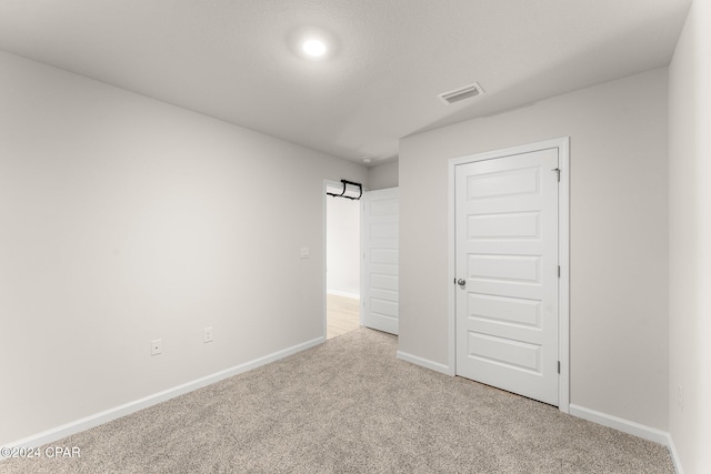 unfurnished bedroom with a closet and light colored carpet