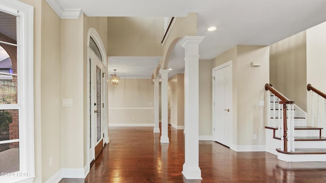 entryway with a notable chandelier, dark hardwood / wood-style flooring, crown molding, and decorative columns