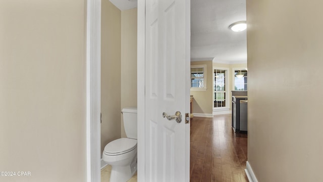 bathroom featuring toilet, wood-type flooring, and ornamental molding