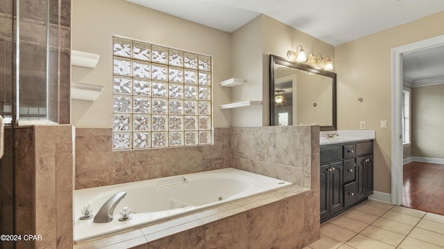 bathroom with tile patterned flooring, a relaxing tiled tub, and vanity