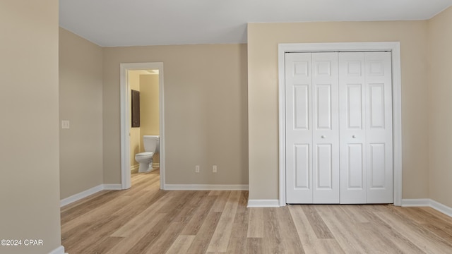 unfurnished bedroom featuring connected bathroom, a closet, and light hardwood / wood-style flooring