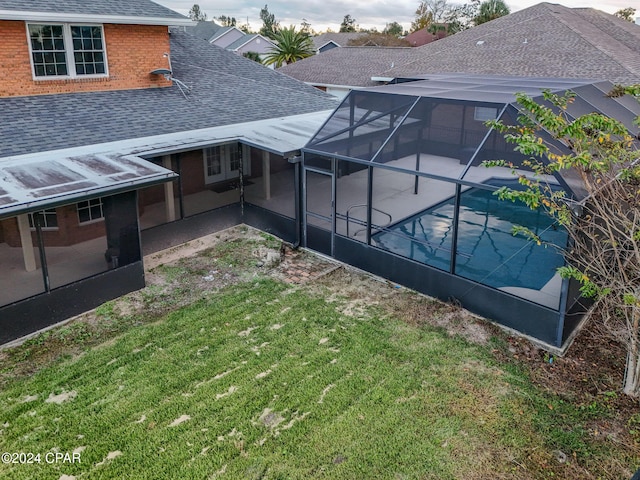 back of house featuring glass enclosure, a yard, and a patio