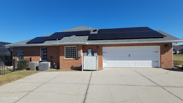 view of front facade with central AC, solar panels, and a garage