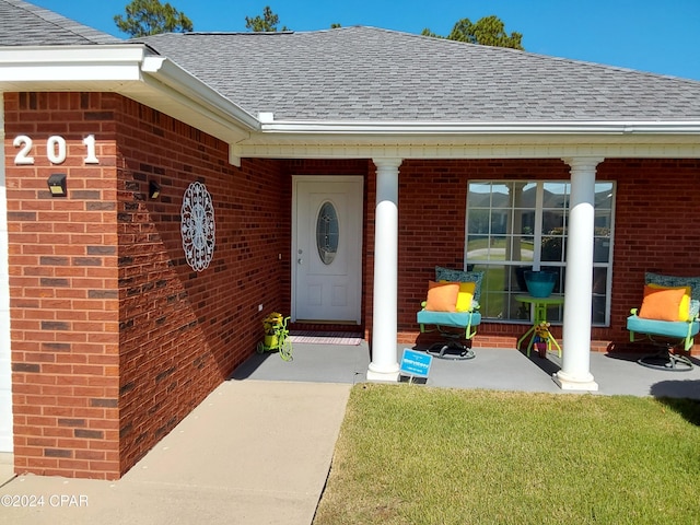 property entrance with covered porch and a yard