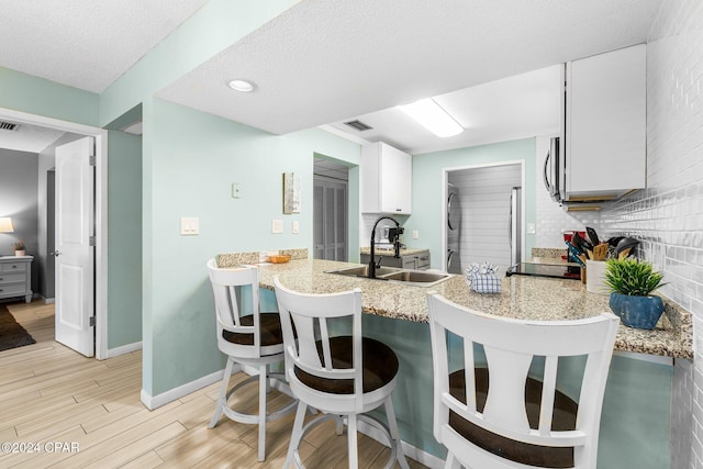 kitchen with white cabinets, sink, tasteful backsplash, stacked washer / drying machine, and stainless steel appliances