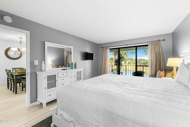 bedroom featuring access to outside, an inviting chandelier, and light hardwood / wood-style floors