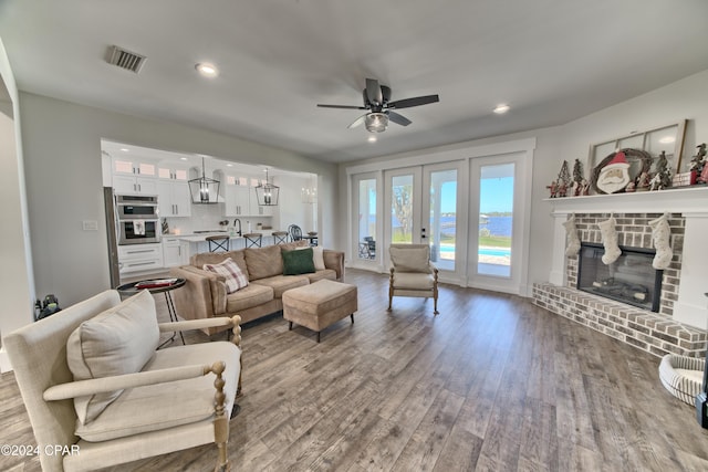 living room featuring a fireplace, light hardwood / wood-style floors, and ceiling fan with notable chandelier