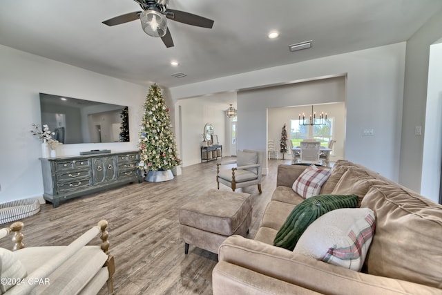 living room with wood-type flooring and ceiling fan with notable chandelier