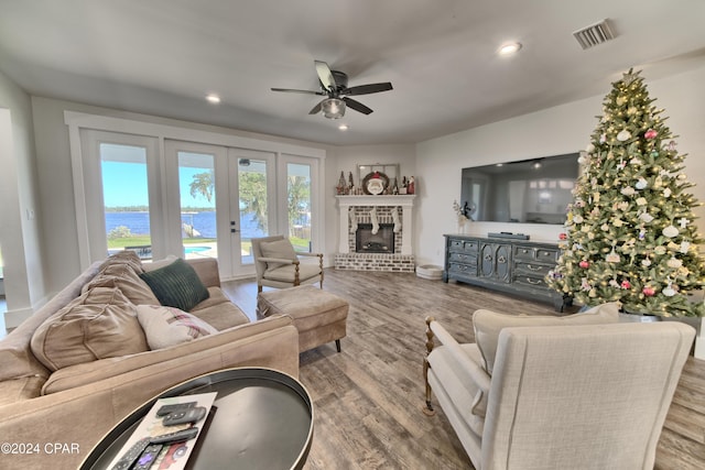 living room featuring a brick fireplace, ceiling fan, french doors, and hardwood / wood-style flooring